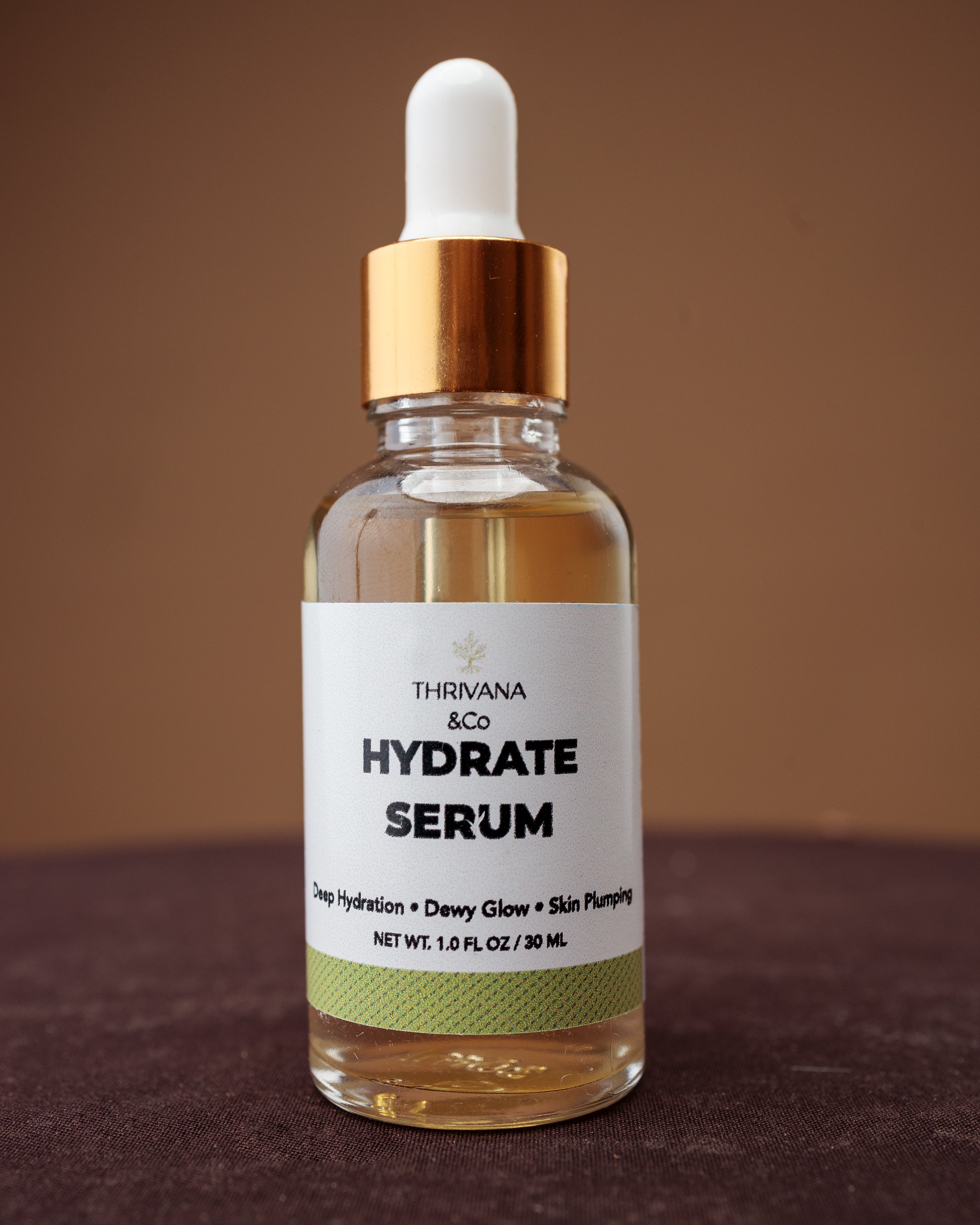 Thrivana & Co Hydrate Serum bottle on a brown background